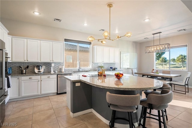 kitchen with white cabinets, decorative light fixtures, a center island, and dishwasher