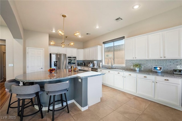 kitchen featuring hanging light fixtures, white cabinetry, appliances with stainless steel finishes, and a center island