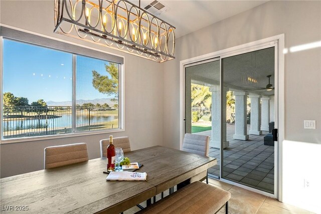 tiled dining space featuring a water view and ceiling fan