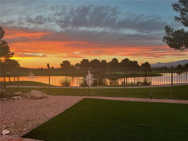 yard at dusk featuring a water view