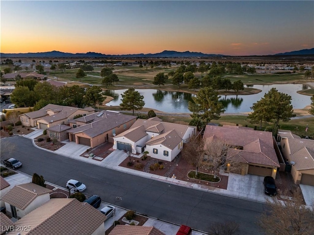 aerial view at dusk featuring a water and mountain view