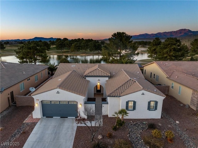 aerial view at dusk featuring a water and mountain view