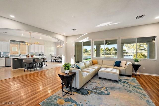 living room with light hardwood / wood-style flooring, a wealth of natural light, and a chandelier