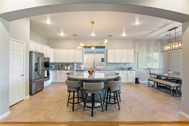 kitchen with decorative light fixtures, a center island, appliances with stainless steel finishes, decorative backsplash, and white cabinets