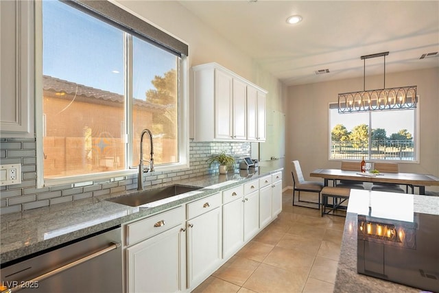 kitchen with stone counters, pendant lighting, white cabinetry, dishwasher, and sink