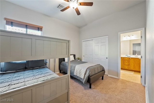 bedroom with ensuite bathroom, light carpet, ceiling fan, and a closet