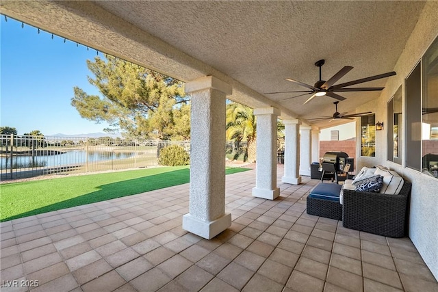 view of patio / terrace featuring a water view, ceiling fan, an outdoor living space, and a grill