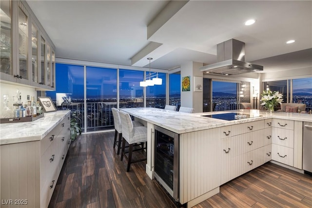 kitchen with decorative light fixtures, island exhaust hood, light stone counters, black electric cooktop, and beverage cooler