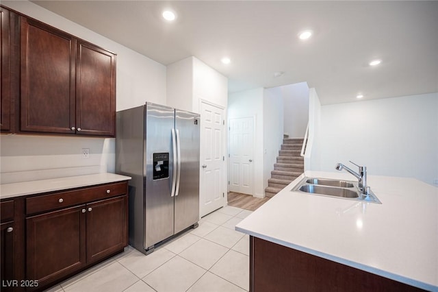 kitchen featuring stainless steel refrigerator with ice dispenser, sink, dark brown cabinetry, and light tile patterned floors