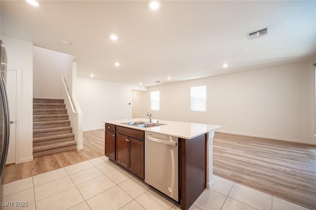 kitchen featuring sink, light tile patterned flooring, stainless steel dishwasher, a center island with sink, and dark brown cabinets