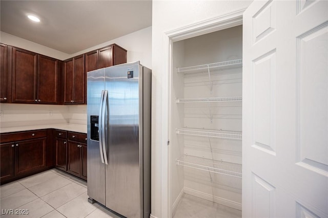 kitchen featuring stainless steel fridge with ice dispenser, dark brown cabinetry, and light tile patterned floors