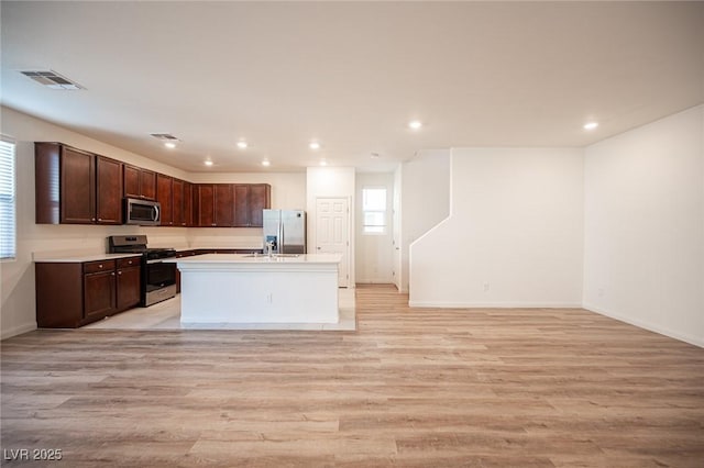 kitchen featuring light hardwood / wood-style floors, an island with sink, dark brown cabinets, and appliances with stainless steel finishes