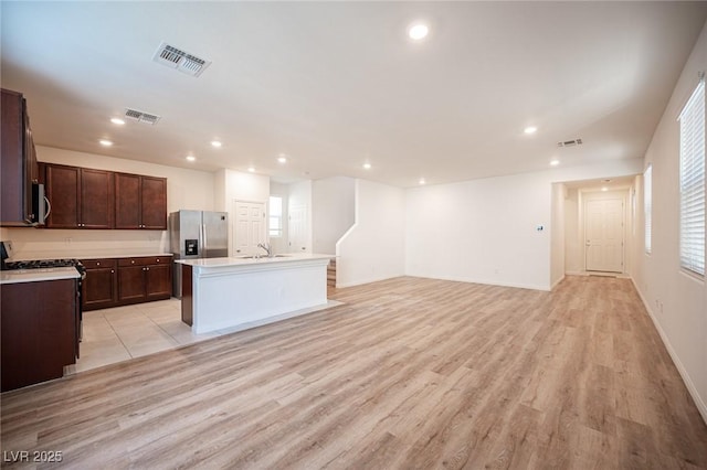 kitchen with sink, a center island with sink, light hardwood / wood-style flooring, and appliances with stainless steel finishes