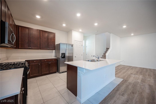 kitchen with sink, dark brown cabinets, a center island with sink, and appliances with stainless steel finishes