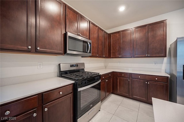 kitchen with dark brown cabinets, light tile patterned floors, and stainless steel appliances