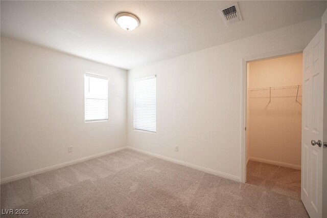 unfurnished bedroom with a closet, light colored carpet, and a spacious closet