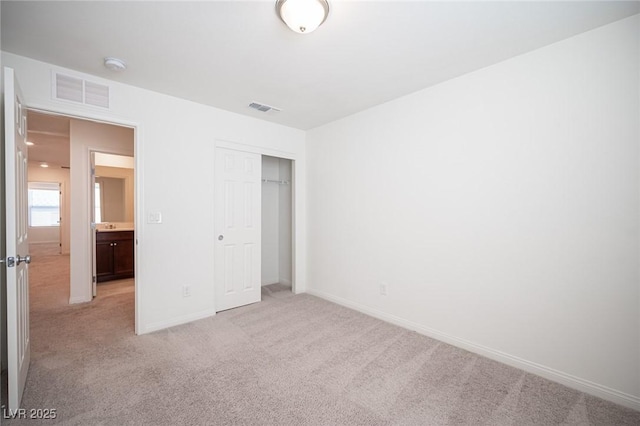 unfurnished bedroom with light colored carpet and a closet