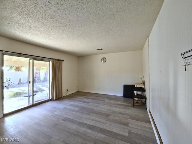 unfurnished room featuring a textured ceiling and light hardwood / wood-style flooring