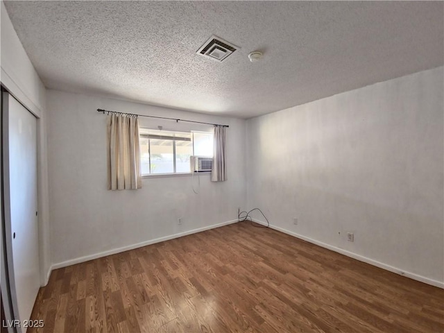 spare room featuring wood-type flooring, a textured ceiling, and cooling unit