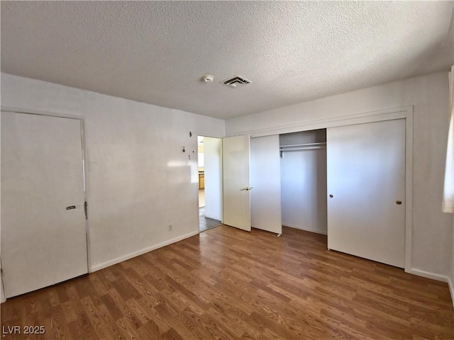 unfurnished bedroom with a closet, hardwood / wood-style floors, and a textured ceiling