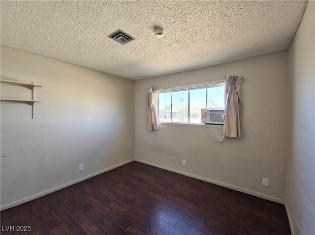 unfurnished room featuring cooling unit, a textured ceiling, and dark hardwood / wood-style flooring