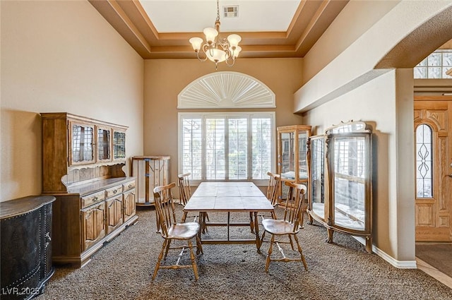 dining room with a notable chandelier, a towering ceiling, and carpet