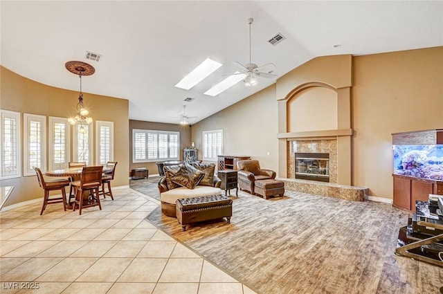 living room featuring ceiling fan with notable chandelier, a wealth of natural light, a high end fireplace, and light tile patterned floors