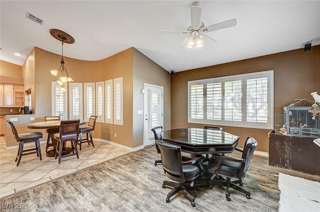 dining space with light tile patterned flooring and ceiling fan with notable chandelier