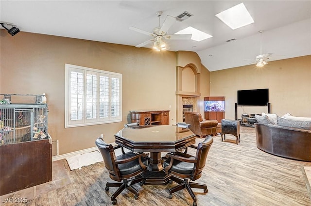 dining area featuring ceiling fan, hardwood / wood-style flooring, and vaulted ceiling with skylight