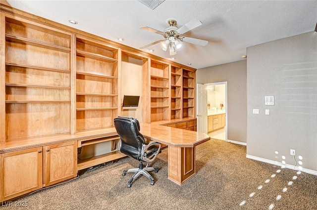 home office with built in features, carpet floors, ceiling fan, and built in desk