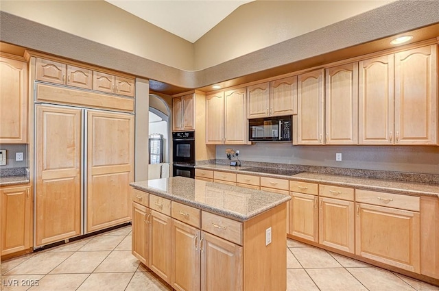 kitchen with light brown cabinets, vaulted ceiling, light tile patterned flooring, a center island, and black appliances