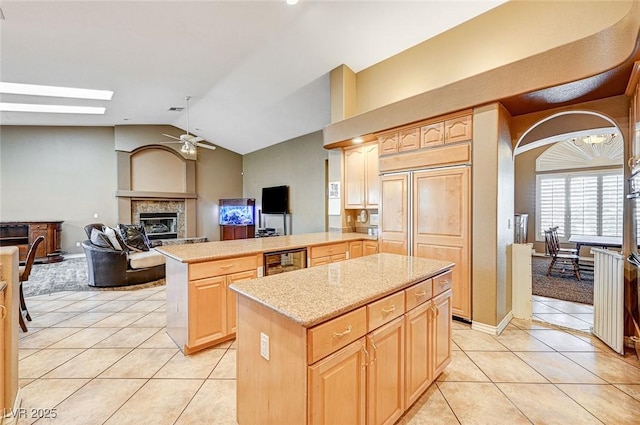 kitchen featuring a kitchen island, light brown cabinets, kitchen peninsula, and vaulted ceiling