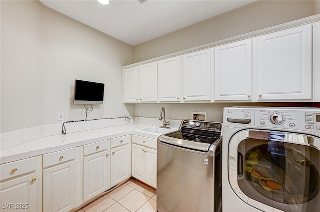 laundry area featuring sink, cabinets, washer and dryer, and light tile patterned floors