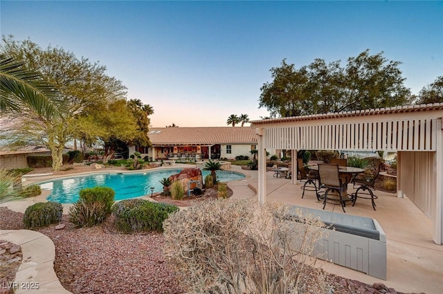 pool at dusk featuring a patio area