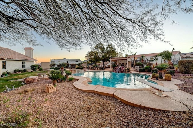 pool at dusk with a diving board and a patio