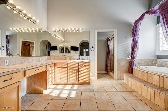 bathroom with tiled tub, tile patterned floors, and vanity