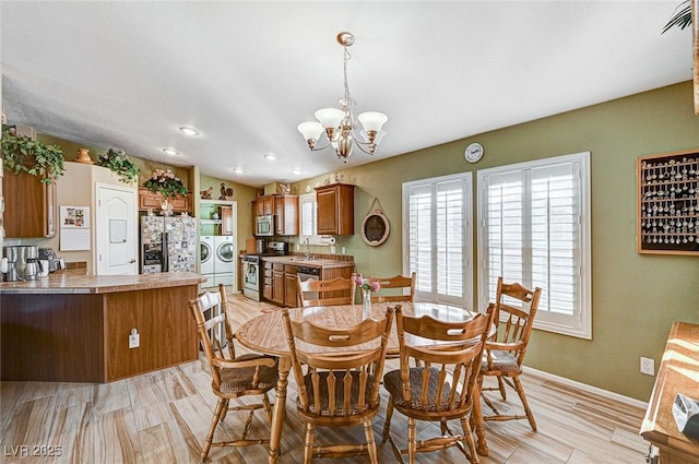 dining room featuring sink, washer and clothes dryer, light hardwood / wood-style flooring, and a chandelier