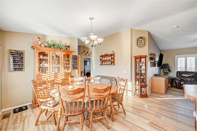 dining space featuring lofted ceiling, light hardwood / wood-style floors, and a notable chandelier