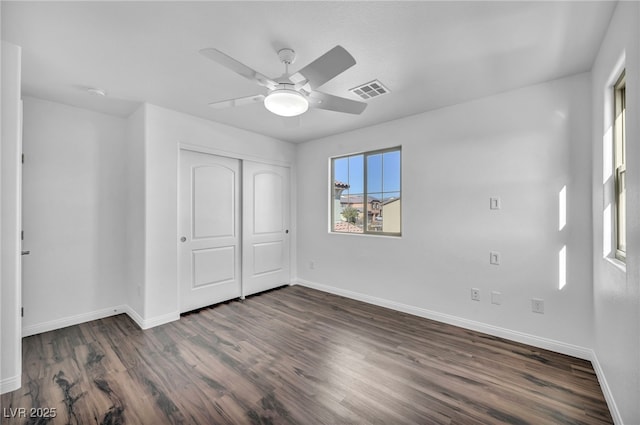 unfurnished bedroom with ceiling fan, dark wood-type flooring, and a closet