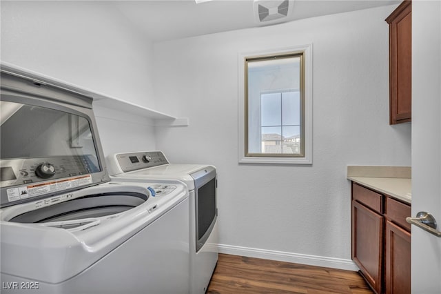 laundry room featuring washer and dryer, dark wood-type flooring, and cabinets