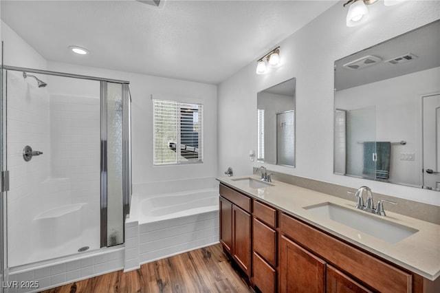 bathroom with vanity, hardwood / wood-style floors, and plus walk in shower