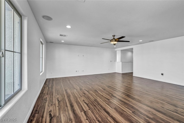 empty room featuring a healthy amount of sunlight, ceiling fan, and dark hardwood / wood-style flooring