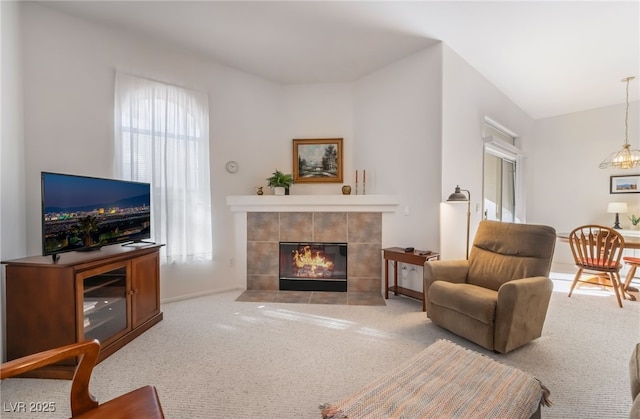 carpeted living room featuring a tile fireplace and vaulted ceiling