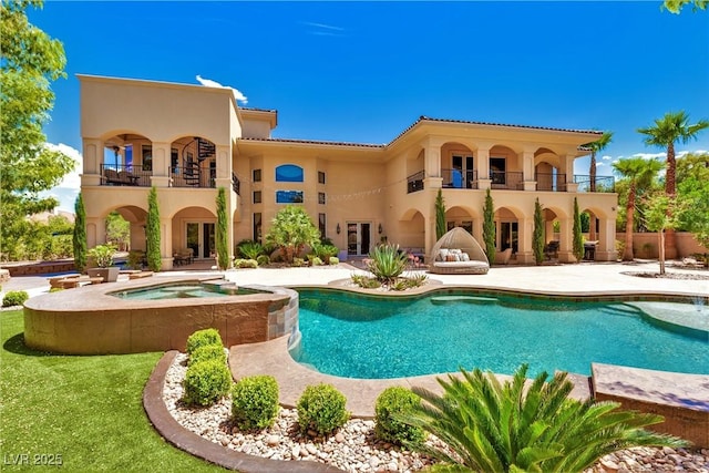 back of house with french doors, a patio, a balcony, and a pool with hot tub