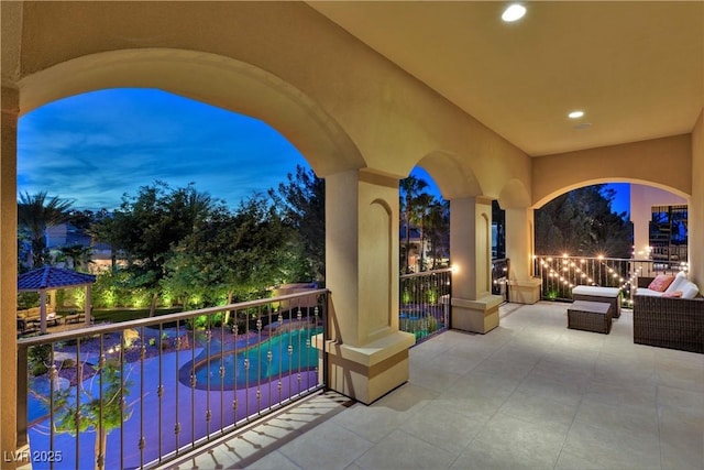 patio terrace at dusk featuring a fenced in pool, a gazebo, and a balcony