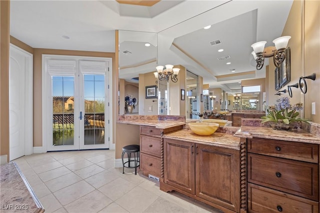 bathroom with french doors, tile patterned floors, vanity, a raised ceiling, and a notable chandelier