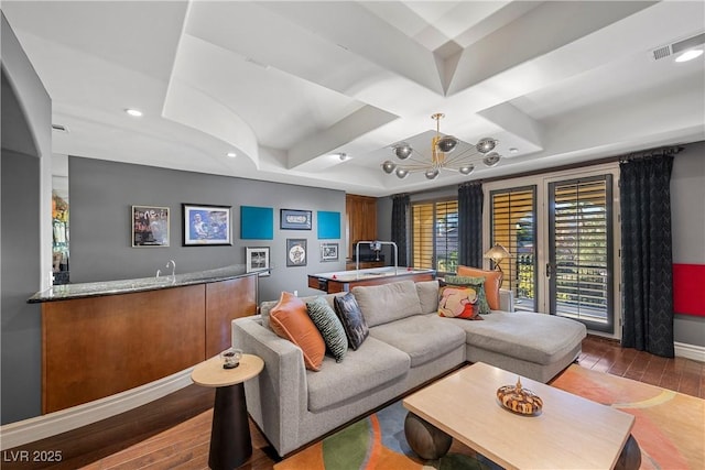 living room with coffered ceiling, wood-type flooring, a raised ceiling, and bar area