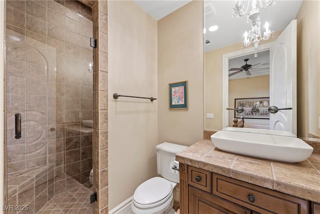 bathroom featuring vanity, ceiling fan, a shower with shower door, and toilet