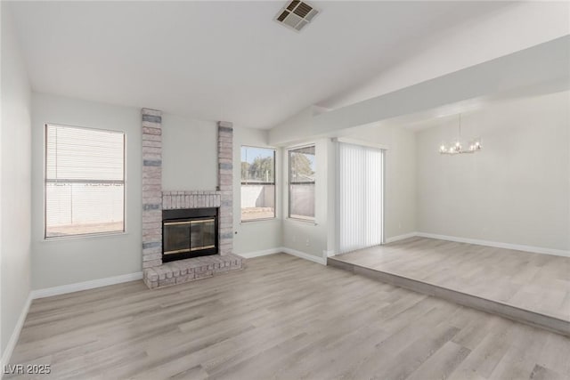 unfurnished living room featuring a fireplace, a chandelier, vaulted ceiling, and light wood-type flooring