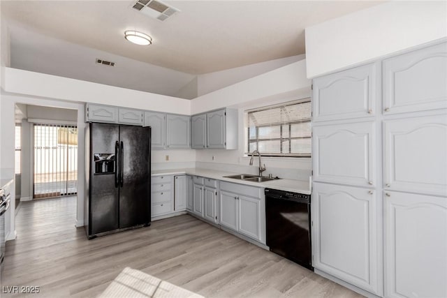 kitchen with sink, gray cabinets, black appliances, vaulted ceiling, and light wood-type flooring